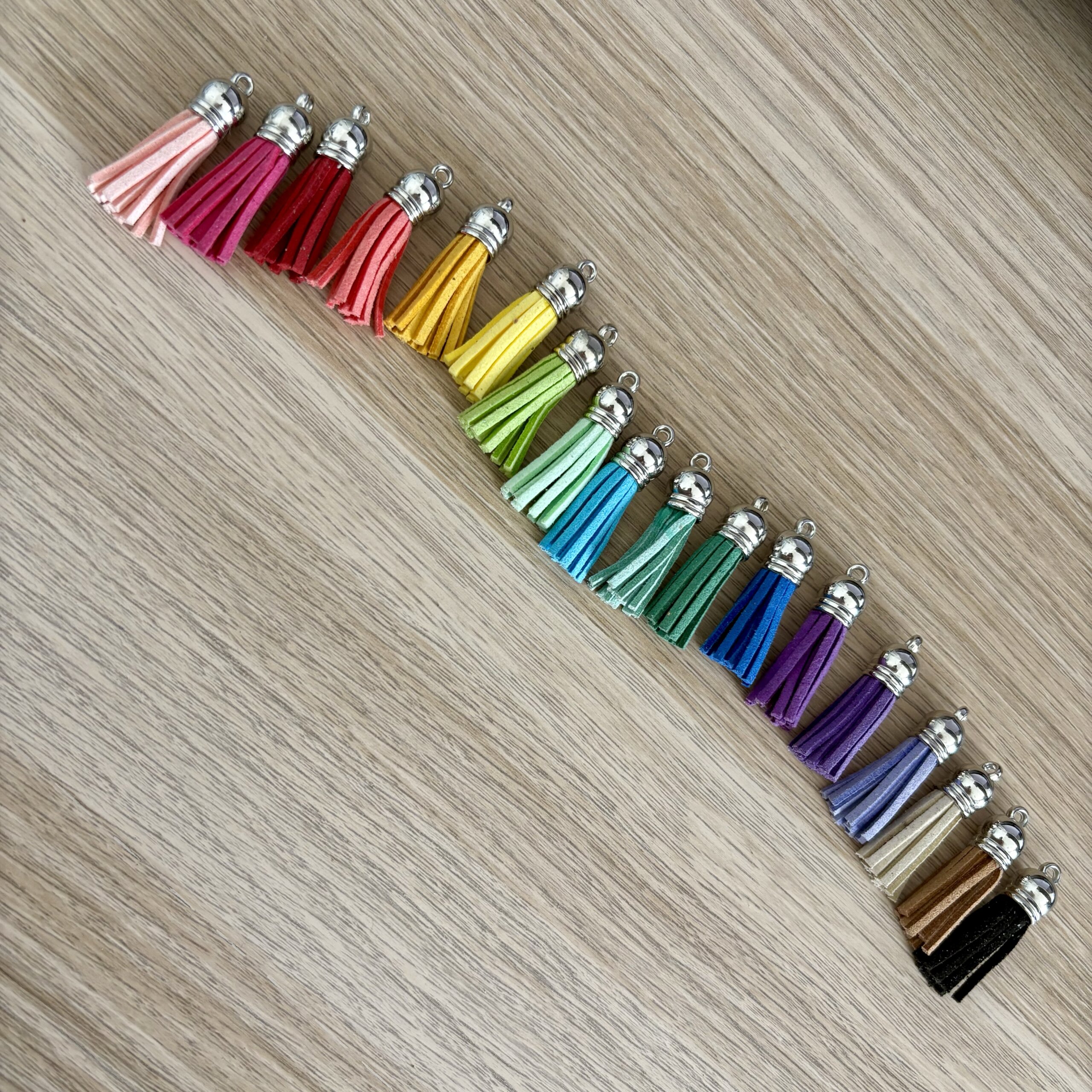 pompons à franges colorés disposés en dégradé, du rose au noir en passant par le jaune, le vert et le bleu, pour personnalisation de porte-clés