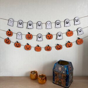 Trois guirlandes d'Halloween en papier représentant des fantômes blancs et des citrouilles oranges accrochées au mur.