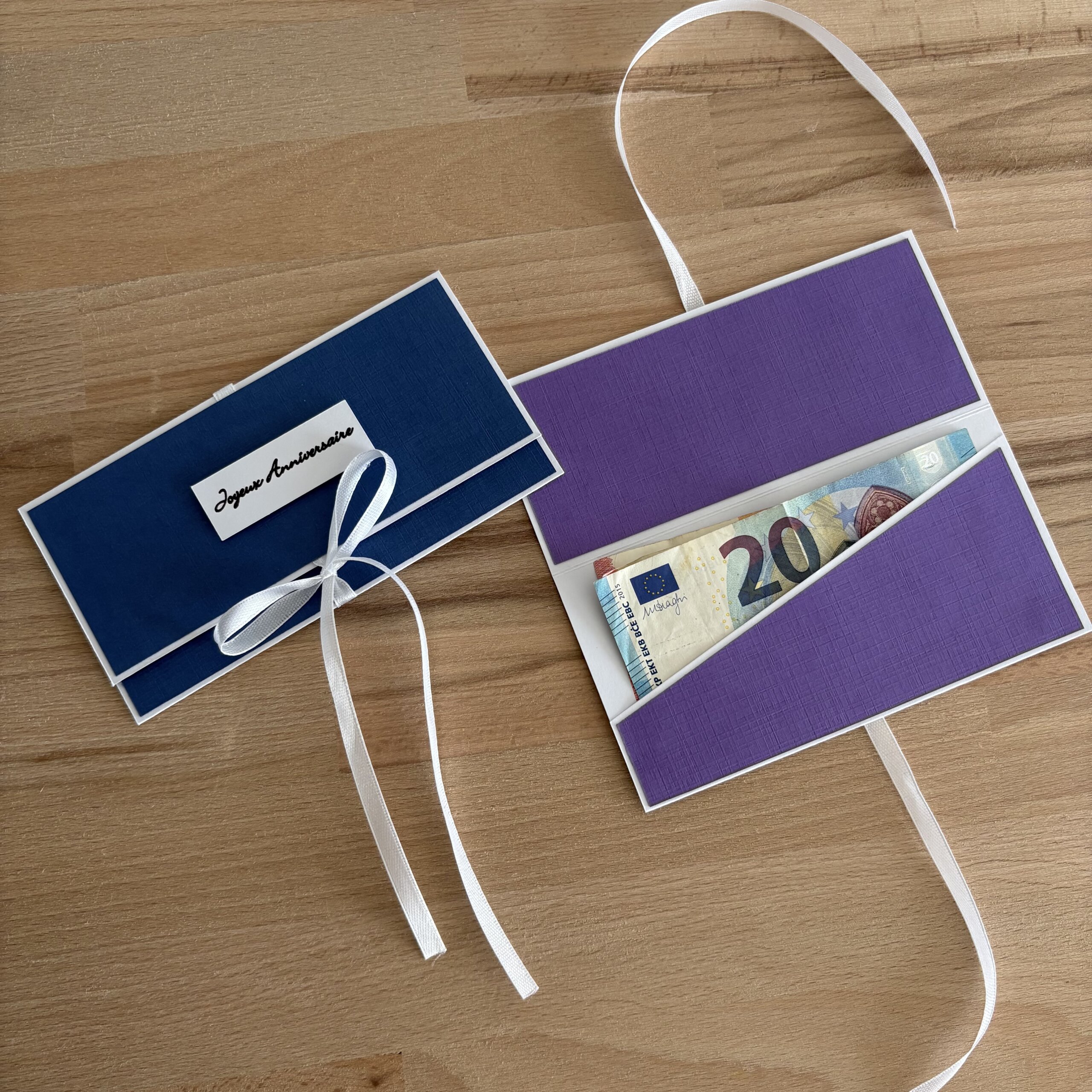 Pochette à billet violette ouverte avec billet et pochette bleu marine avec étiquette Joyeux Anniversaire