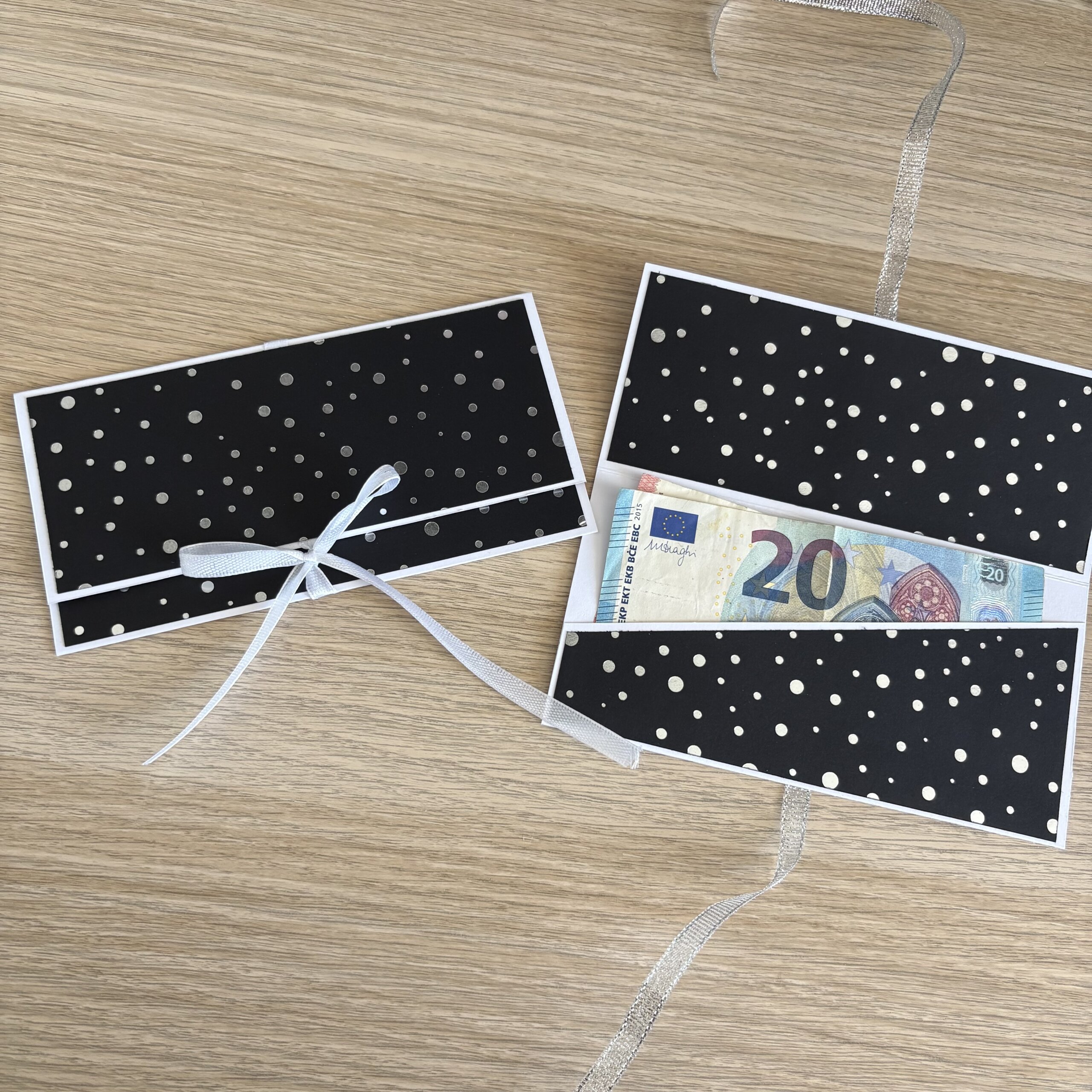Pochette cadeau noire à pois argentés ouverte avec billet glissé dans son emplacement intérieur