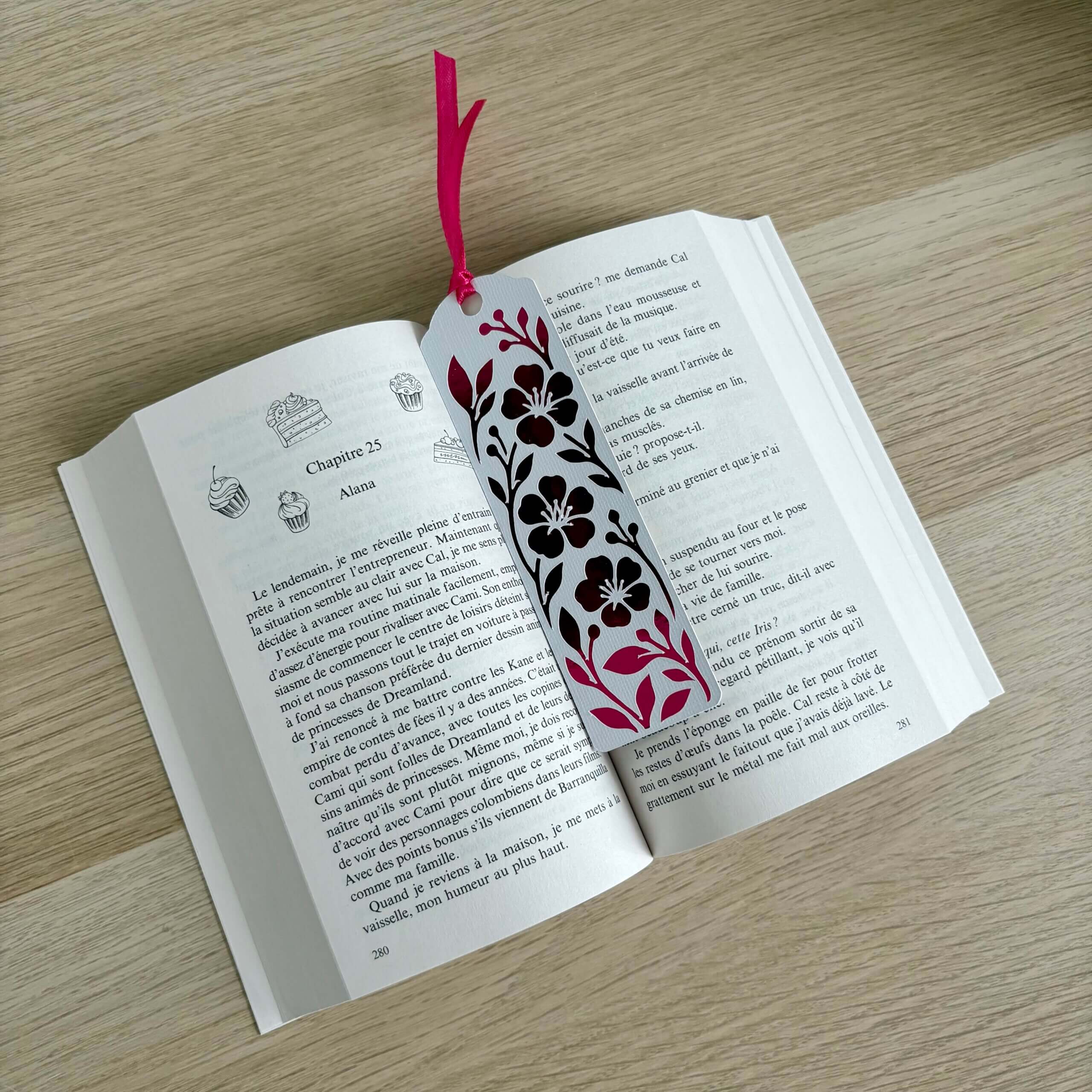Marque-page fleuri rose fuchsia en papier blanc texturé et papier miroir, présenté dans un livre ouvert
